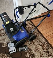 Snow Joe iON15SB-LT snow blower with battery and charger on floor