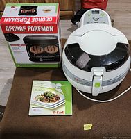 T-fal ActiFry unit, George Foreman grill retail box, ActiFry manual displayed together