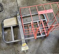 Overall view of black steel carrier frame with attached red wire basket