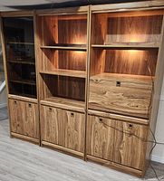 Front view of entire three-section wall unit showing glass door, open shelves, lower cabinets