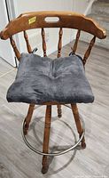 Front view of oak swivel bar stool with dark grey cushion and metal footrest