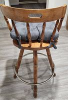 rear view of one stool showing spindle backrest, cushion, swivel seat, legs and footrest