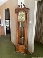 Full view of grandfather clock closed, showing wood case and glass front