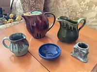 Full set on table showing teapot, two pitchers, blue bowl, candle holder