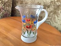 Front view of clear glass jug showing floral print, frosted base and handle