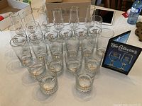 Full set of 24 gold-rimmed Calgary 1988 Olympic glasses with packaging insert