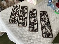 All four copper-tone floral plaques laid out on table