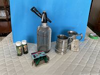Group shot of seltzer bottle, CO2 cartridges, pewter mugs, shakers