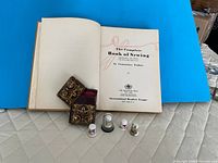 Open sewing book with needle case and four thimbles displayed