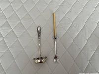 Overall view of sterling sugar spoon and plated pickle fork