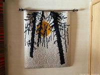 Front view of hand hooked rug hanging on wall with wooden rod