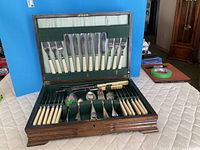 Open oak canteen displaying full flatware set