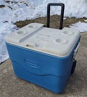 Front view of blue Coleman wheeled cooler with lid closed, handle extended