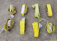 Eight coiled yellow ratchet straps on concrete