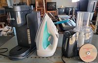 Keurig coffee maker, steam iron, food processor components on table
