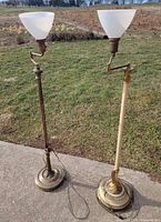Full view of both brass floor lamps standing outdoors