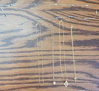 All five necklaces laid out showing relative lengths and pendants