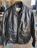 Front view of black leather jacket hanging