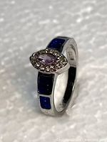 Full view of ring showing lavender center stone, clear halo, blue inlays