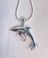 Close-up of dolphin and calf pendant on chain