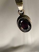 close-up of oval faceted amethyst in silver bezel and bail