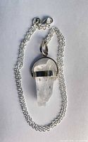 Necklace laid flat showing quartz pendant and chain clasp