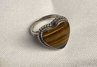 Top view of heart-shaped tiger eye ring in silver bezel