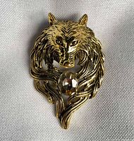 Front view of gold-tone wolf head brooch pendant