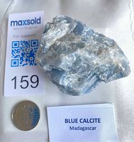 Full view of blue calcite next to coin and label for scale