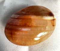 Top view of polished banded carnelian agate palm stone