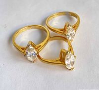 Three gold-tone rings displayed flat showing stones and shanks