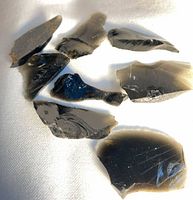 Group of obsidian shards on white fabric