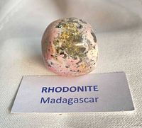 Front view of polished rhodonite stone with label