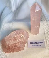 Polished rose quartz tower standing next to rough rose quartz piece with label