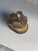 front angled view of smoky quartz cluster on wood base
