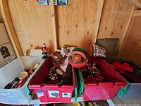 Three storage bins filled with assorted Christmas decorations including nutcrackers, garland, ornaments, decorative tins, pillow