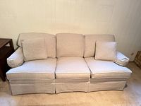 Front view of beige 3-seat sofa showing overall design, cushions, skirt