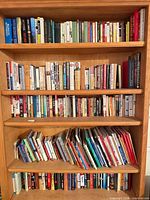 Five wooden shelves filled with assorted hardcover and paperback books