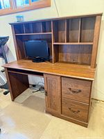 Front view of desk with hutch showing shelves, cubbies, drawers, cabinet and monitor for scale