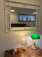 Wall mirror, banker’s lamp, crystal lamp, extension cords visible on tabletop