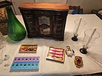 Overall lot showing wooden jewelry box, green vase, hurricane holders, pill organizer, spreaders, fragrance pods