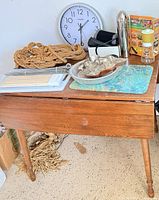 Table with assorted items including clock, macrame rope, kitchenware