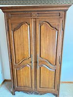 Front view of closed armoire showing paneled doors and carved accents