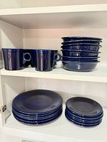 Stacked plates, bowls and mugs on shelves displaying quantities and overall condition