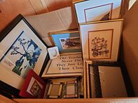 Box containing assorted framed prints, sign, small frames, and empty frames