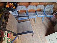 All five chairs grouped: one patio sling armchair, four blue padded folding chairs