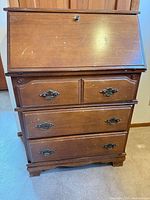 Front view of closed secretary desk showing drawers and hardware