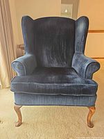 Front view of navy blue velvet wingback armchair showing removable cushion and cabriole legs