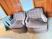 Two mauve velvet armchairs beside round sage-covered side table