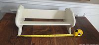 Top view of cream wood book rack with tape measure showing length